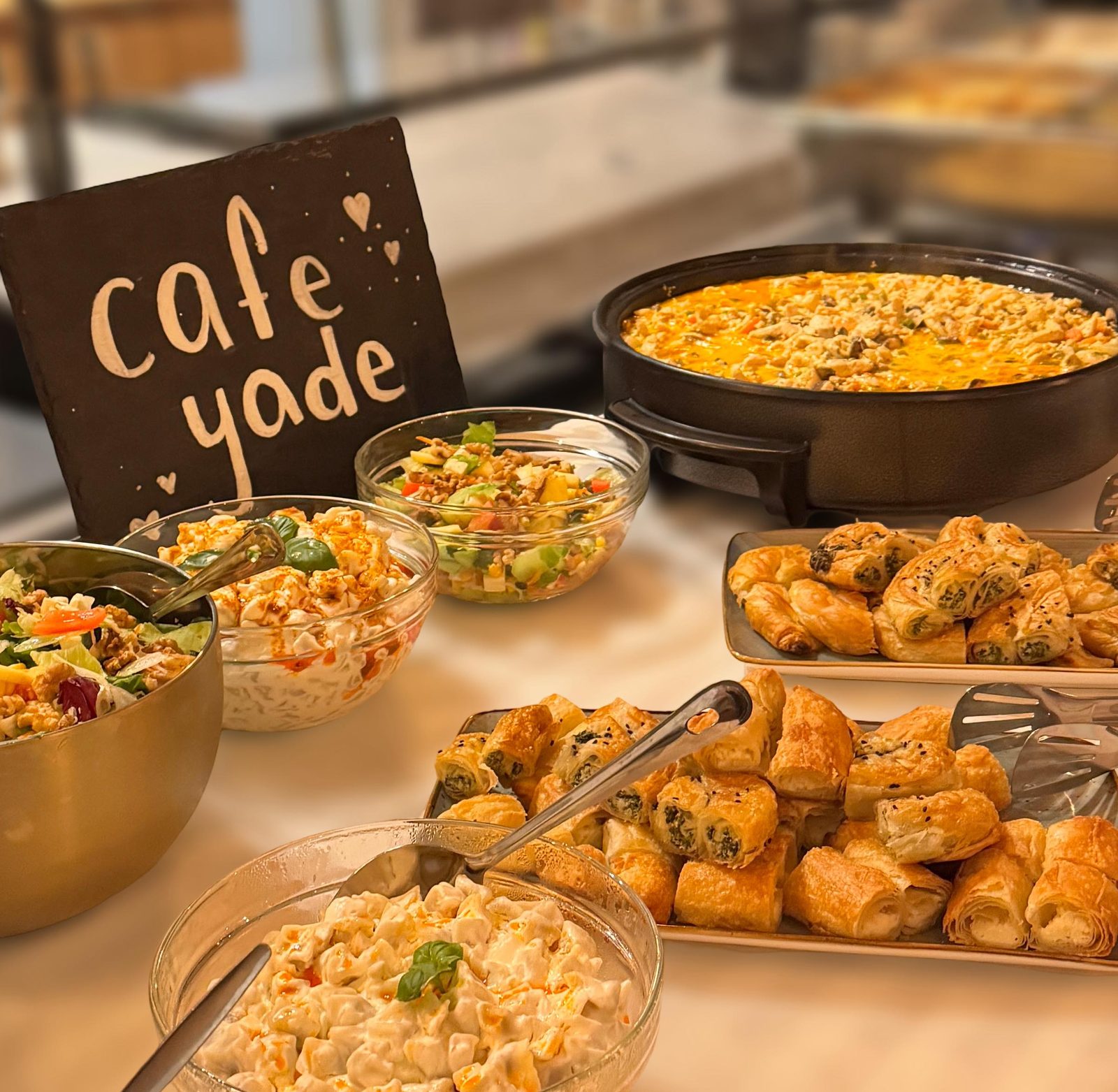 Buffet mit warmen Gerichten und Salaten unter dem Café-Yade-Schild