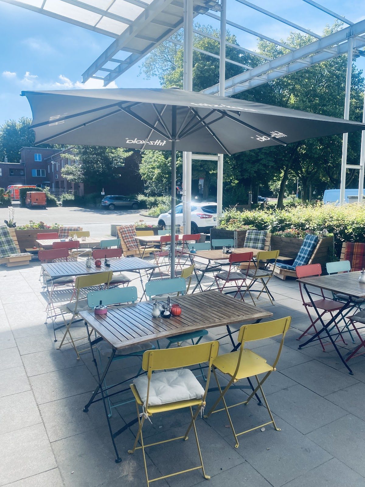 Terrasse des Café Yade mit weißen Sonnenschirmen und Bistrostühlen